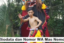 Young shirtless boy dancing in front of a performer in a colorful costume outdoors; banner overlay reads 'Biodata dan Nomor WA Mas Nemo'