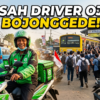 Gojek rider in green jacket on a scooter in the foreground, with a packed crowd and a yellow train at Bojonegede station in the background (Indonesia).